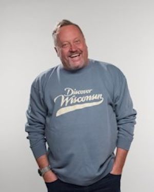 Photograph of a smiling man wearing a blue sweatshirt with text that says "Discover Wisconsin"